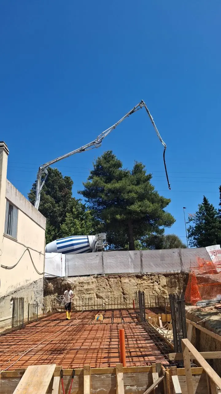 Getto di calcestruzzo su un solaio, con il braccio della pompa in alto.